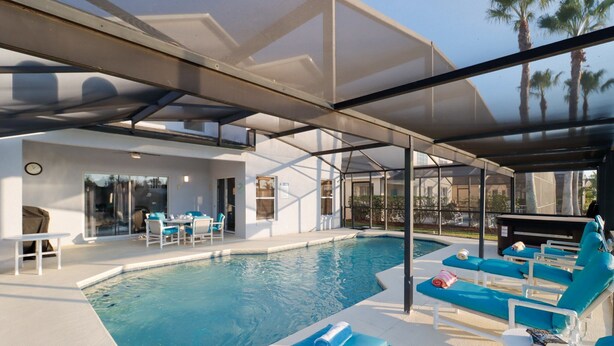 Un espace piscine moderne avec des chaises longues et un coin salon abrité.