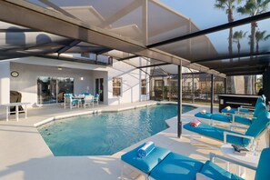 Un espace piscine moderne avec des chaises longues et un coin salon abrité.