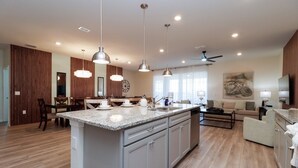 Una cocina amplia con una isla grande, suelo de madera e iluminación colgante.