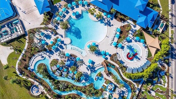 Vista aérea de un complejo turístico con una piscina central, varias toboganes acuáticos y tumbonas.