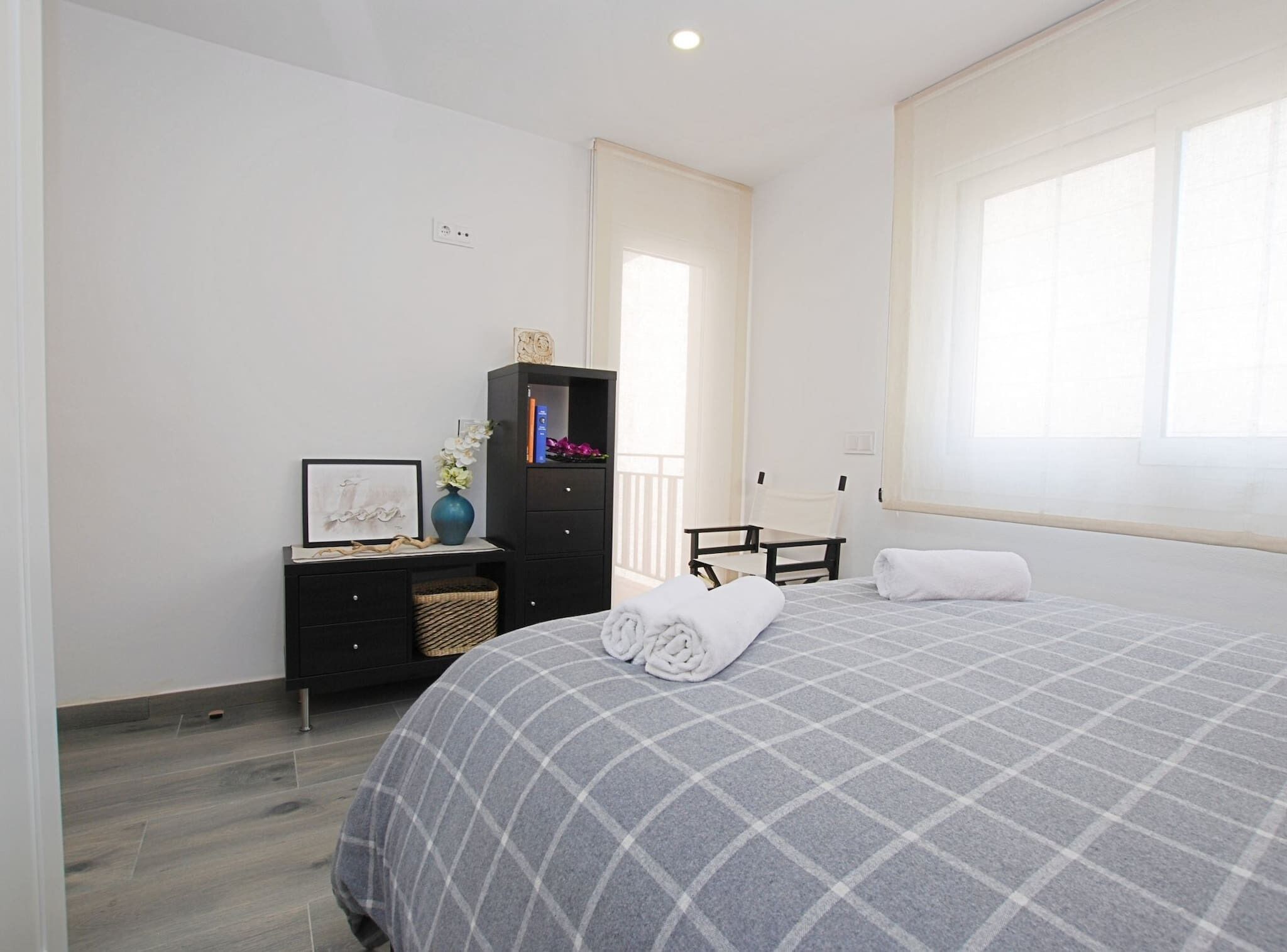Une chambre à coucher avec un lit, une commode, une chaise et une fenêtre.
