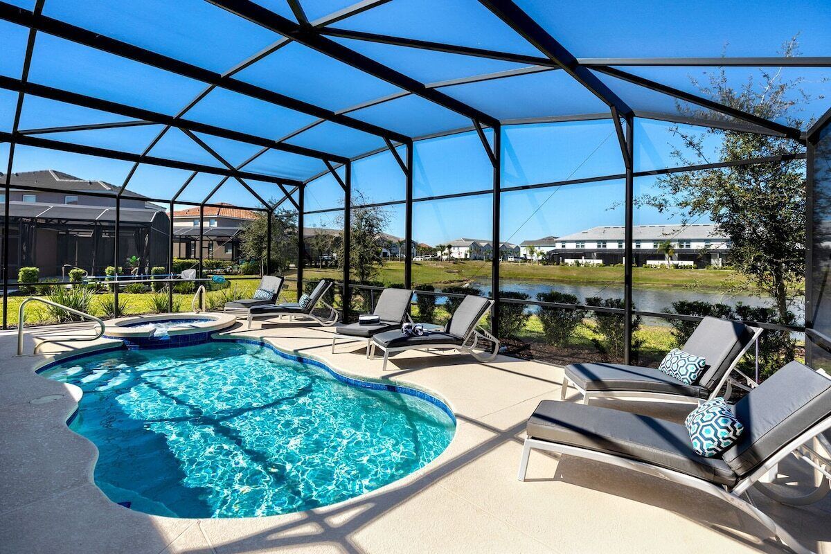 A covered outdoor swimming pool with lounge chairs and a hot tub.