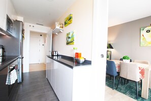 A modern kitchen with a central island, a dining area with a table and chairs, and artwork on the walls. - Cozy Home · Nice apartment with pool and private terrace (Mataró)