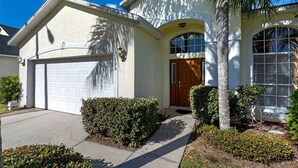 Une maison à deux étages avec un garage, une porte d’entrée et un petit jardin.