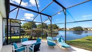 Une terrasse couverte, aménagée avec du mobilier d’extérieur, et offrant une vue sur un lac.