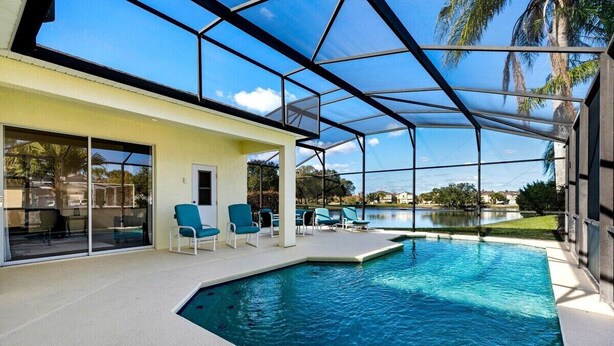 Une piscine couverte à l’eau d’un bleu cristallin, entourée de chaises longues et dotée d’une porte vitrée donnant sur un espace patio.