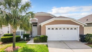 A residential house with a white garage, a palm tree, and a well-maintained lawn.