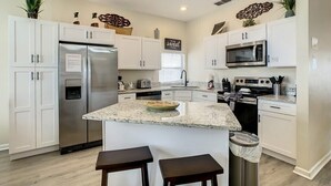 A modern kitchen with white cabinets, stainless steel appliances, and a granite countertop.