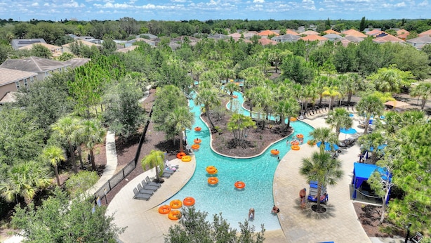 Un resort con piscina central, rodeado de palmeras y sillas de descanso.