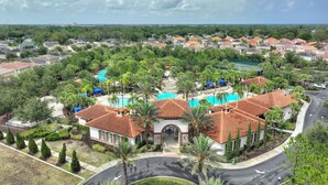 Un barrio residencial con piscina, palmeras y casas de tejas rojas.
