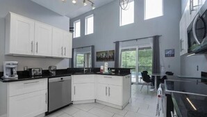 A modern kitchen with white cabinets, a black countertop, and a built-in oven.
