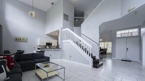 A spacious living area with a modern staircase, a dining area, and a kitchen.