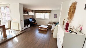 Un salón amplio con un piano, sofá y mesa de comedor.