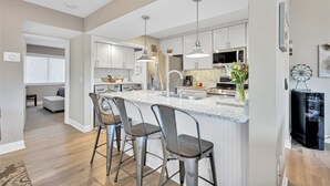 A modern kitchen with a central island, bar stools, stainless steel appliances, and pendant lighting. - 265 Turnberry @ Palmetto Dunes | Golf View Escape | Walk to Beach | Pool, Golf & Tennis (Hilton Head Island)