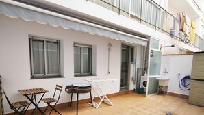 A small outdoor patio with a table, chairs, a drying rack, and a washing machine.