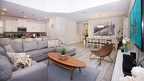 A modern living room with a grey sofa, a wooden coffee table, and a TV on a stand. - Modern 5BR Oasis w/ Pool, Spa & Resort Perks (Davenport)