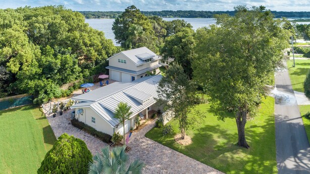 Una casa de dos pisos con una amplia terraza y vista a un lago.