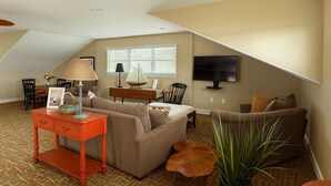 Una sala de estar acogedora con un sofá, una mesa de centro, un televisor y un comedor con sillas y una mesa.