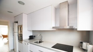 A modern kitchen with white cabinetry, a stainless steel sink, and a built-in oven.
