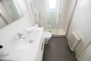 A modern bathroom with a white sink, toilet, and glass shower enclosure. - Narciso views - Community Pool (Vilassar de Mar)