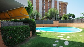 A swimming pool with a grassy area and a building in the background.