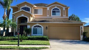 A two-story house with a garage, a well-maintained lawn, and a mailbox. - Spacious 4BR Villa with Private Pool Near Disney (Davenport)