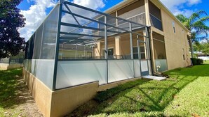 A modern building with a glass enclosure, a covered outdoor area, and a well-maintained lawn. - Spacious 4BR Villa with Private Pool Near Disney (Davenport)