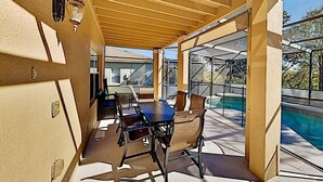An outdoor patio with a table and chairs, a pool, and a covered area with a pergola. - Spacious 4BR Villa with Private Pool Near Disney (Davenport)