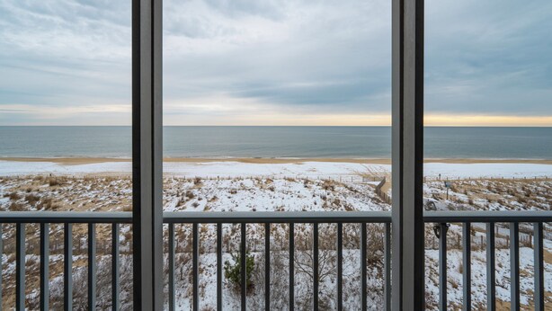 A view from a balcony overlooking a beach with snow on the ground and a cloudy sky. - Wonderful Ocean Views from this 2 Bedroom Oceanfront With a Pool (Ocean City)