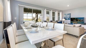 Un comedor moderno con una mesa blanca dispuesta para seis personas, rodeada de sillas color beige.