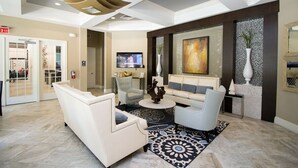 Un moderno vestíbulo con un sofá blanco, sillones, una mesa de centro y un televisor.