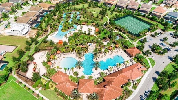 Vista aérea de una zona residencial con piscina central, canchas de tenis y casas circundantes.