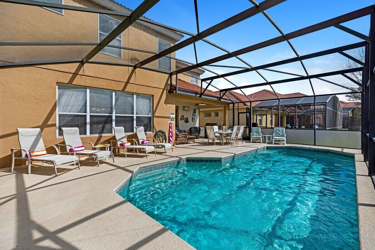 An indoor swimming pool with lounge chairs and a covered patio area.