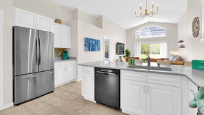 A modern kitchen with white cabinetry, stainless steel appliances, and a dishwasher.
