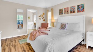 A bedroom with a large bed, a chair, a nightstand, and a mirror.