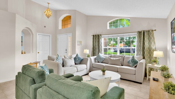 A spacious living room with a large sofa set, a coffee table, and a chandelier.
