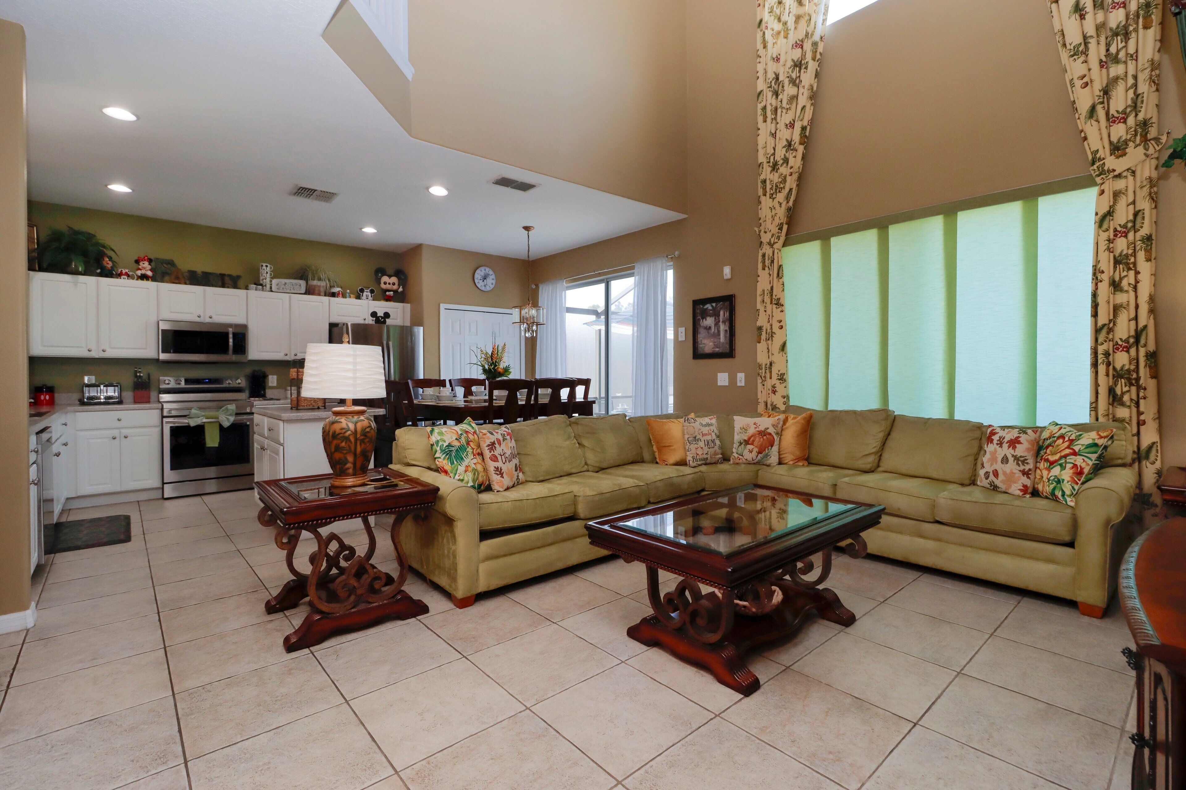 A spacious living room with a sectional sofa, a glass coffee table, and a dining area with a chandelier.