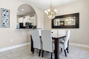 A dining area with a chandelier, a large mirror, and a view into the kitchen. - Solterra Luxury Oasis: Resort Fees Included (Davenport)