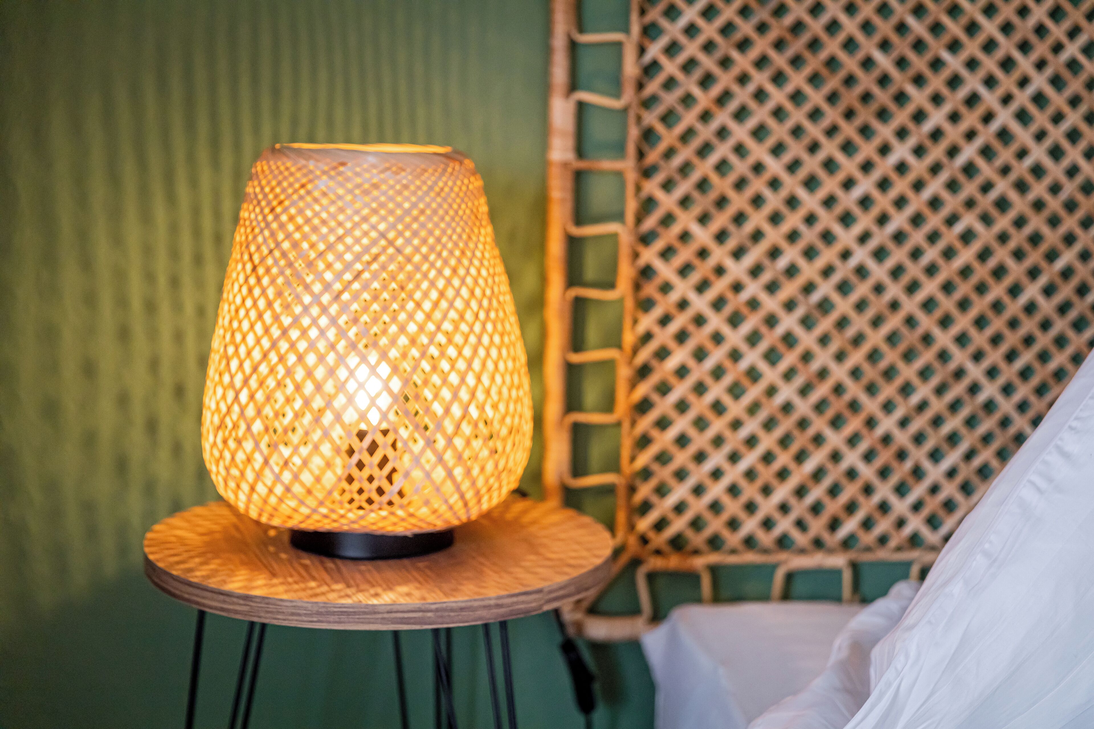Eine Lampe auf einem runden Holztisch mit einer gewebten Rückenlehne.