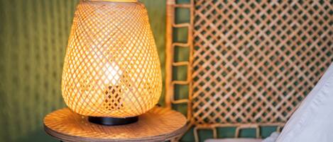 Eine Lampe auf einem runden Holztisch mit einer gewebten Rückenlehne.