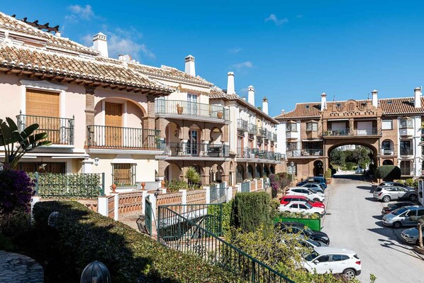 A residential area with multi-story buildings, balconies, and a street with parked cars.