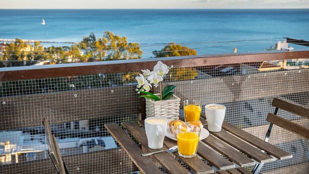 Un balcón con mesa dispuesto para el desayuno, con vistas a la costa.