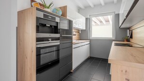 Una cocina moderna con electrodomésticos integrados, encimera de madera y ventana que proporciona luz natural.