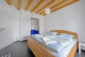 Un dormitorio con una cama de madera, una puerta blanca, un armario azul y un ventilador de techo.