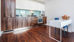 A modern kitchen with wooden cabinets, a white countertop, and a built-in oven. - Basildon - 2-bed - Sleeps 5 - Near Train Station (Basildon)
