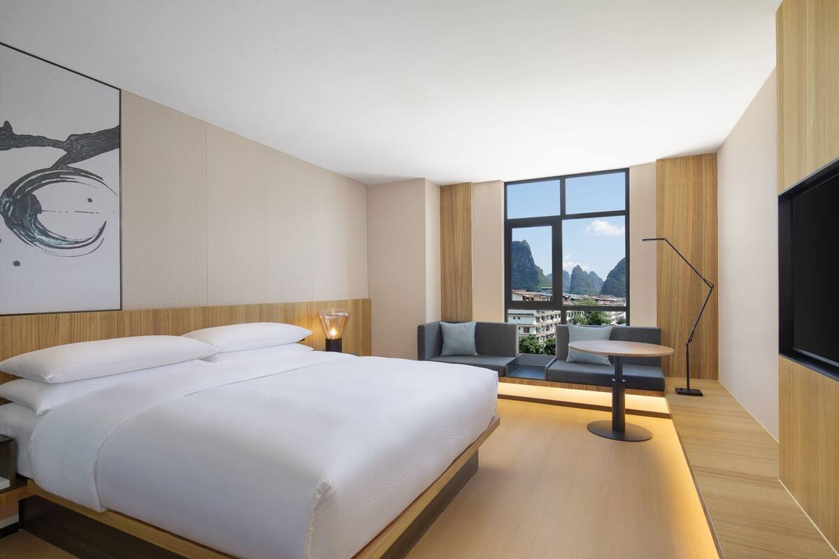Una habitación de hotel moderna con una cama grande, un área de descanso con vistas y un televisor de pantalla plana.