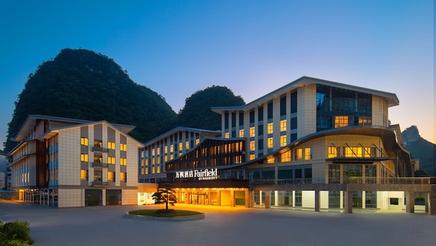 A multi-story hotel with a modern design, featuring a prominent entrance and a landscaped area in front. - Fairfield By Marriott Yangshuo (Guilin)