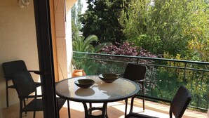 A balcony with a round glass table, two chairs, and a potted plant. - FULLY EQUIPPED APARTMENT IN ONE OF THE BEST BEACHES ON THE COSTA BRAVA (Sant Feliu de Guíxols)