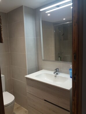 Ein Badezimmer mit Waschbecken, Spiegel und Dusche.