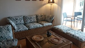 A living room with a sofa, two armchairs, a coffee table, and a floor lamp. There are three framed pictures on the wall. - FULLY EQUIPPED APARTMENT IN ONE OF THE BEST BEACHES ON THE COSTA BRAVA (Sant Feliu de Guíxols)
